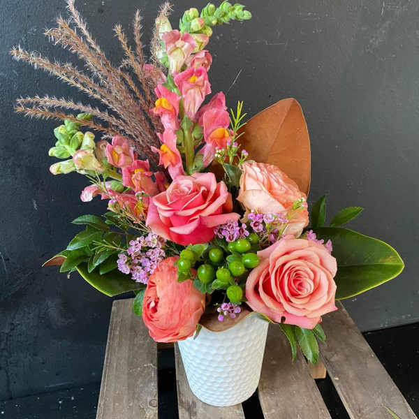 Pink roses and snapdragons arranged in a white vase
