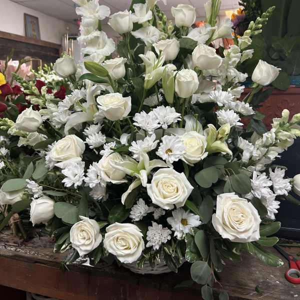 Large white floral arrangement with roses, lilies, and daisies