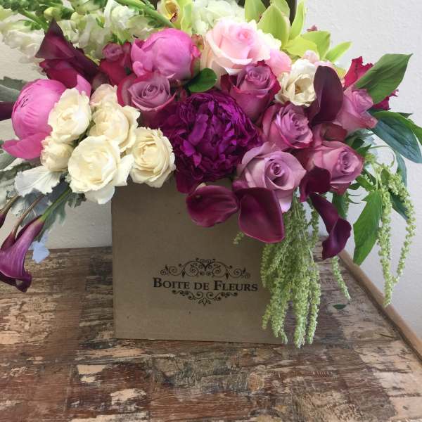Mixed pink, white, and purple flowers arranged in a box
