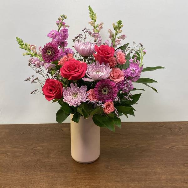 Mixed pink and purple flowers arranged in a white vase