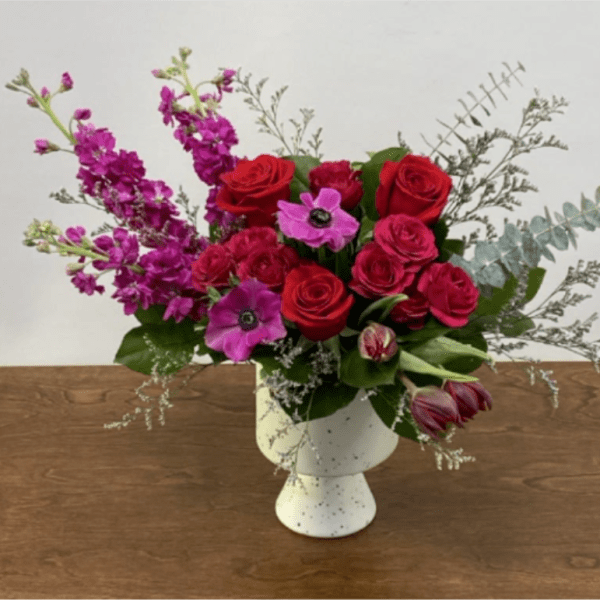 Red and pink flower arrangement in a white vase