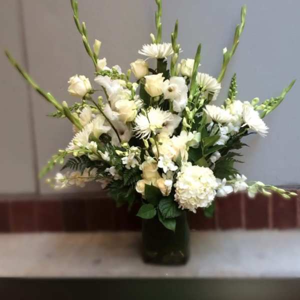 White floral sympathy arrangement in a dark vase