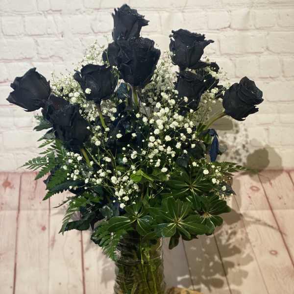 Bouquet of black roses with baby's breath in a glass vase