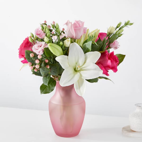 Pink and white flower bouquet in a frosted pink vase