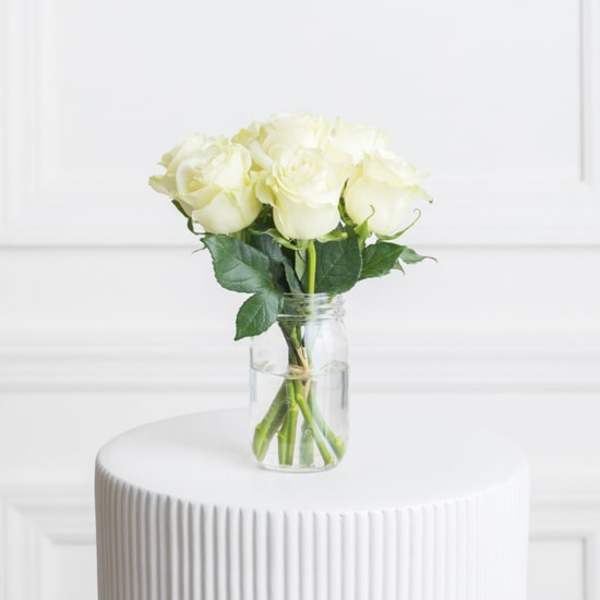 White roses in a clear glass jar vase