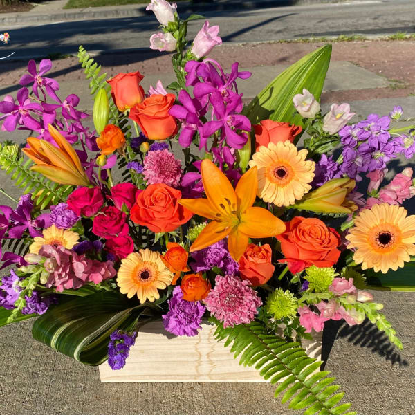 Bright mixed bouquet in a wooden box with orange, purple, and pink flowers