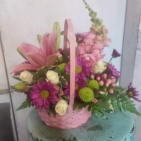 Pink lilies and purple daisies in a pink basket