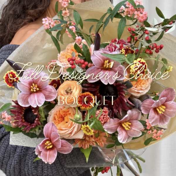Handheld bouquet of pink and peach flowers wrapped in paper
