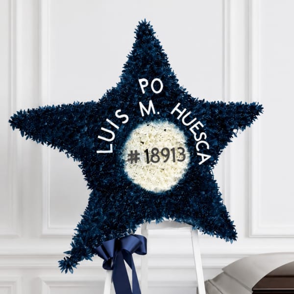 Star-shaped floral tribute on a stand with white center and dark blue flowers