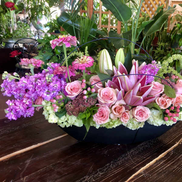 Pink roses and lilies arranged in a low black container