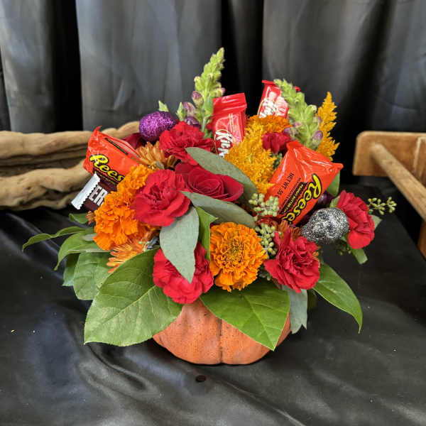 Pumpkin-shaped floral arrangement with candy bars and bright flowers