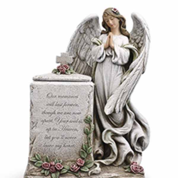 Angel statue beside a memorial stone with small pink roses