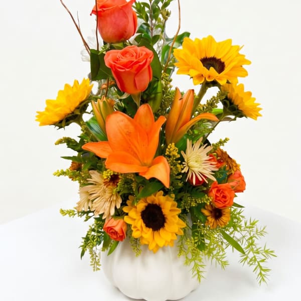 Orange roses and lilies with sunflowers in a white vase
