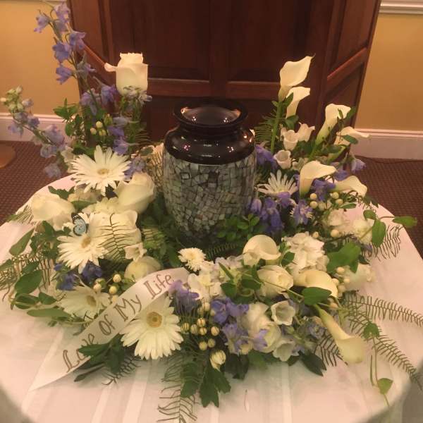 White and lavender floral wreath around a black urn