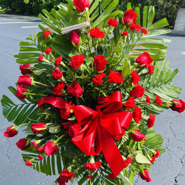 Large red rose and carnation standing spray with a red bow