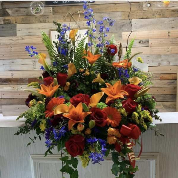 Large mixed bouquet with red roses, orange lilies, and blue flowers