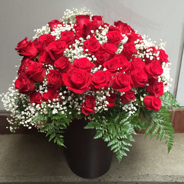 Red roses arranged in a black vase with white baby's breath