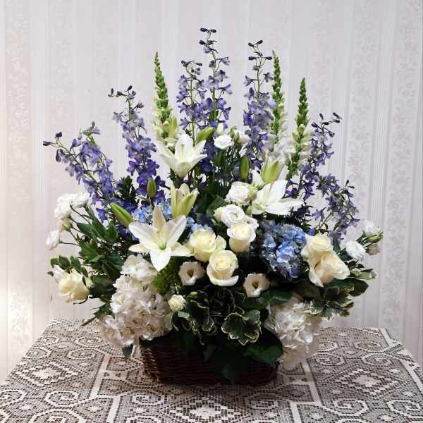 Large basket arrangement with white lilies, roses, hydrangeas, and purple delphinium