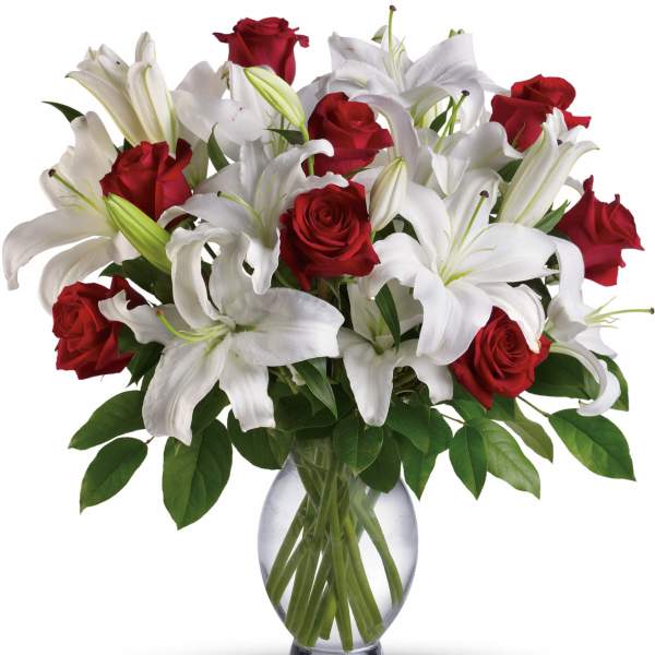Red roses and white lilies arranged in a clear glass vase