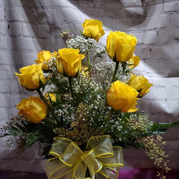Yellow roses arranged in a glass vase with a yellow ribbon bow