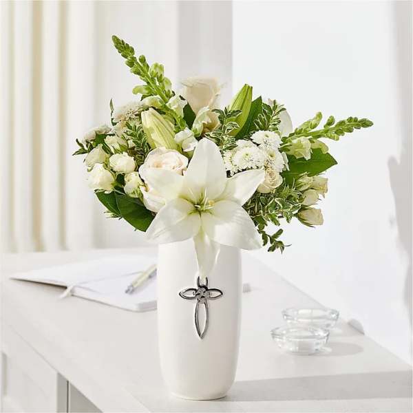 White floral arrangement in a tall vase with a cross emblem