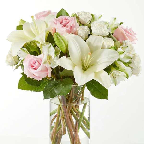 Pink and white bouquet of roses and lilies in a clear glass vase