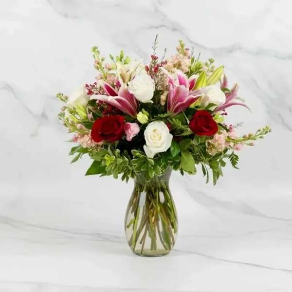 Bouquet of red and white roses with pink lilies in a glass vase