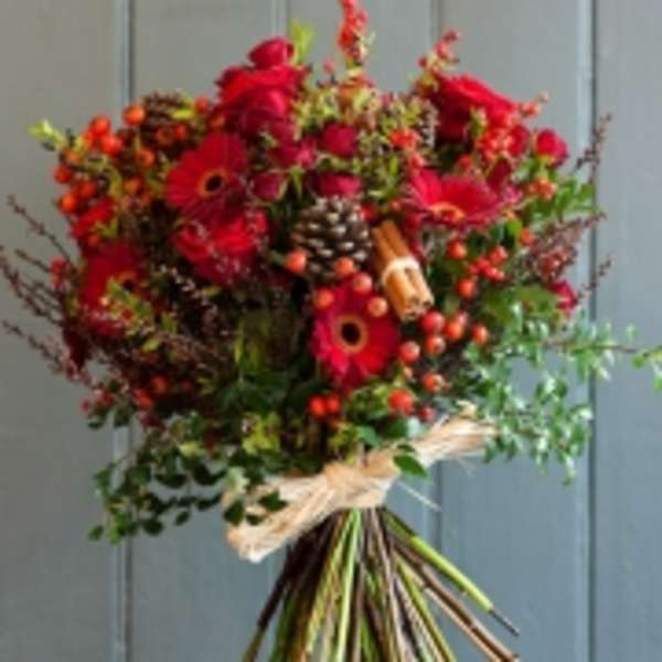 Bouquet of red flowers with berries and pinecones tied with a ribbon