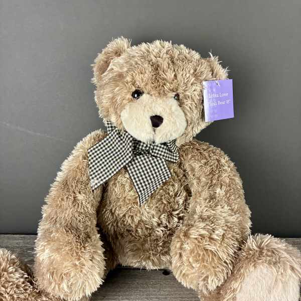 Large tan plush teddy bear with a checkered bow sitting on a wooden surface