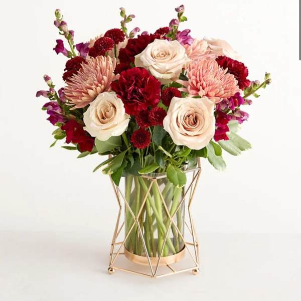 Bouquet of cream roses, pink mums, and red carnations in a glass vase