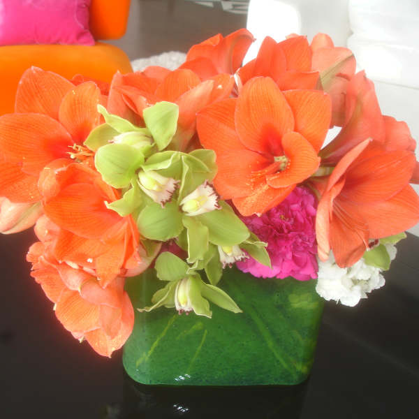 Orange and green floral arrangement in a green vase on a table