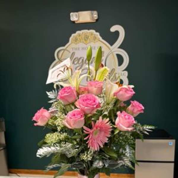 Pink roses and lilies arranged in a tall glass vase