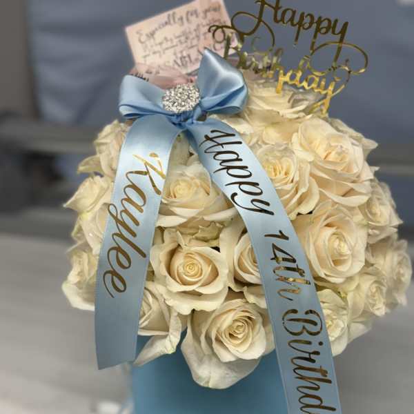 Cream rose arrangement in a blue hat box with a birthday ribbon