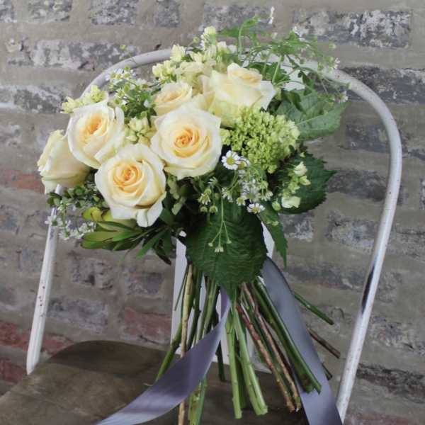 Bouquet of cream roses with small white filler flowers and a ribbon
