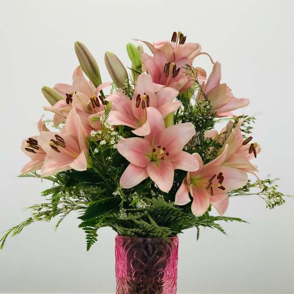 Pink lilies arranged in a pink glass vase