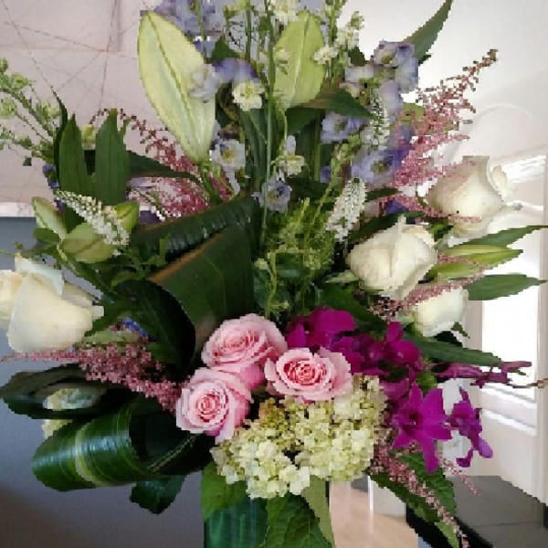 Tall mixed bouquet in a glass vase with pink, white, and purple flowers