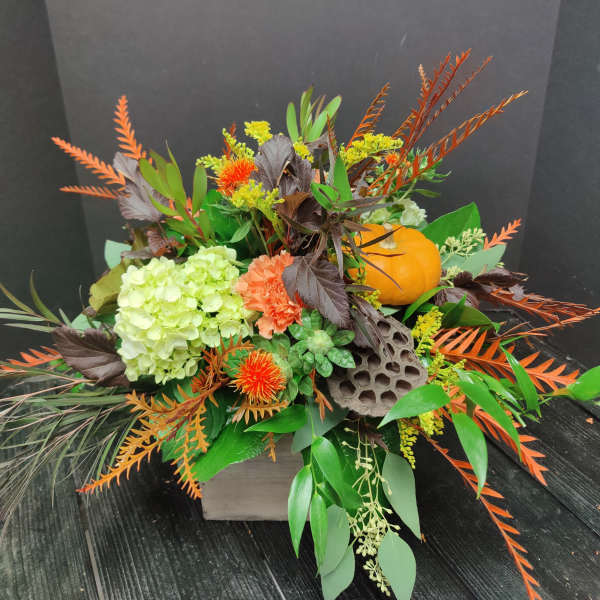 Autumn floral arrangement with hydrangea, orange blooms, and a small pumpkin in a box