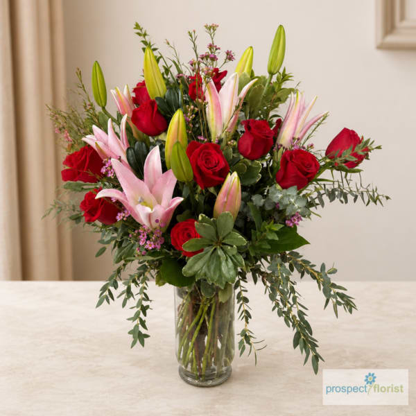 Red roses and pink lilies arranged in a clear glass vase