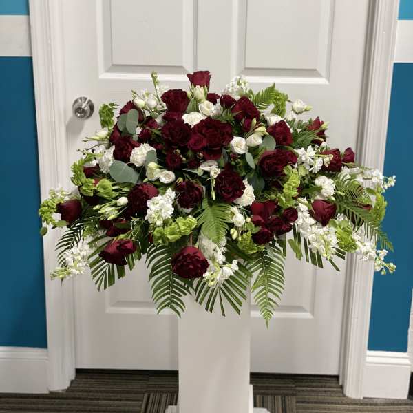 Large burgundy and white floral arrangement on a white pedestal