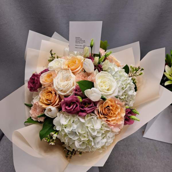 Bouquet of peach, white, and magenta roses with white hydrangeas
