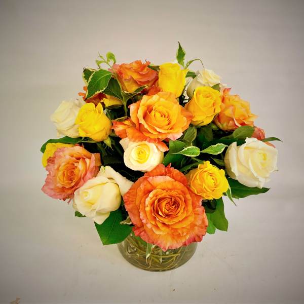 Bouquet of orange, yellow, and white roses in a glass vase