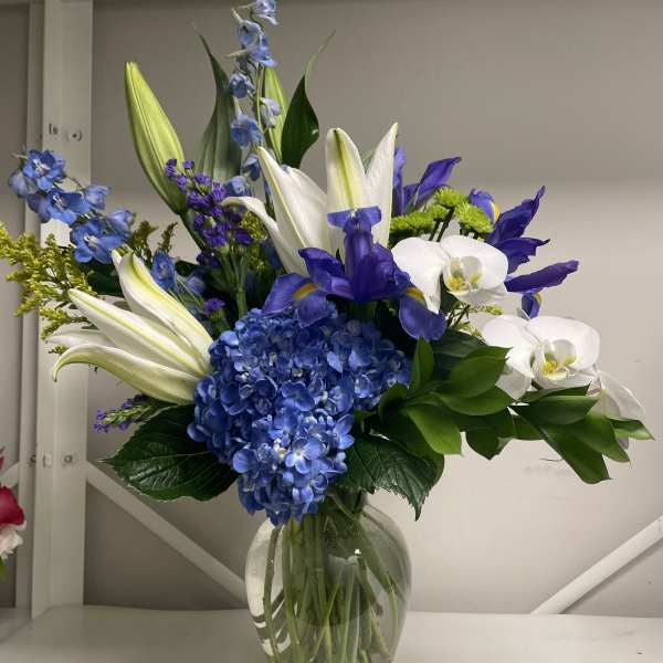 Blue and white floral arrangement in a clear glass vase