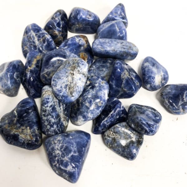 Pile of polished blue stones with white veining on a white background