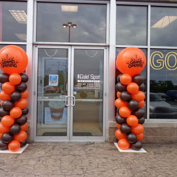 Orange and black balloon columns flank a storefront entrance