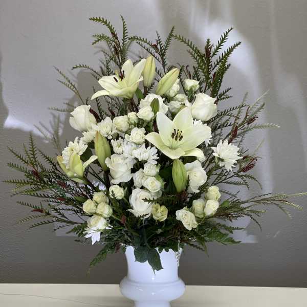 White lilies and roses arranged in a white vase