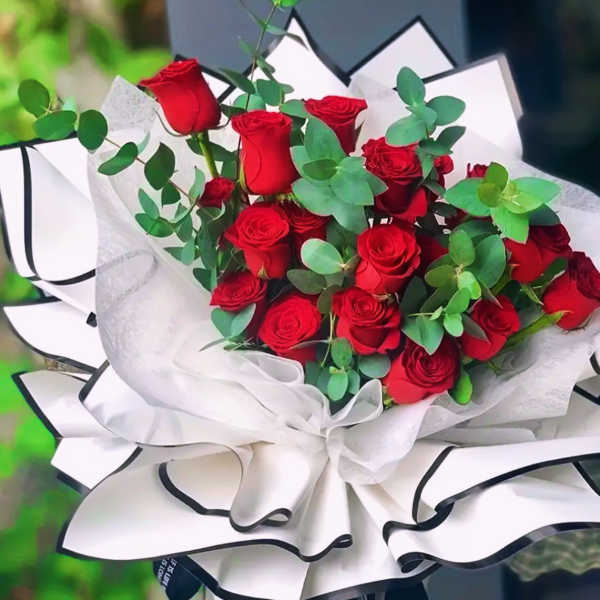 Bouquet of red roses wrapped in white paper with black trim