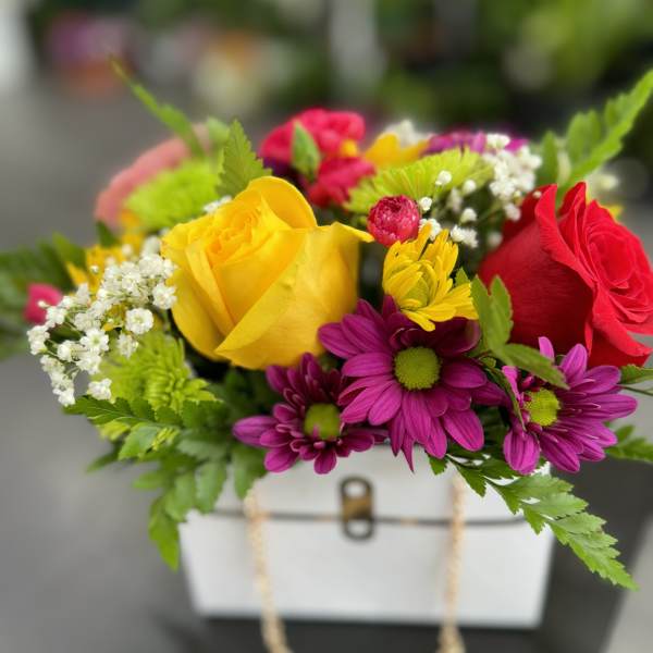 Colorful bouquet of roses and daisies in a white gift box