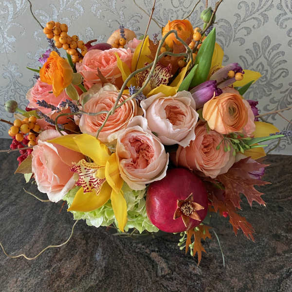 Mixed bouquet of peach roses, yellow orchids, and a pomegranate