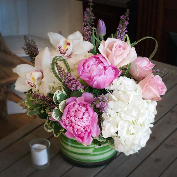 Pink and white floral arrangement in a green striped vase