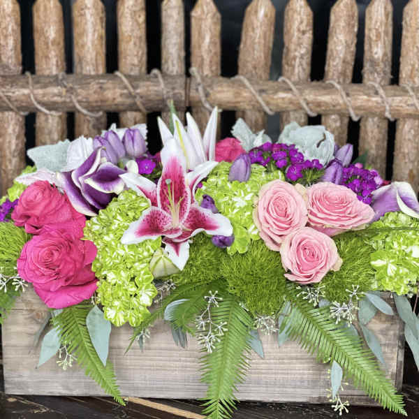 Pink and purple floral arrangement in a wooden box